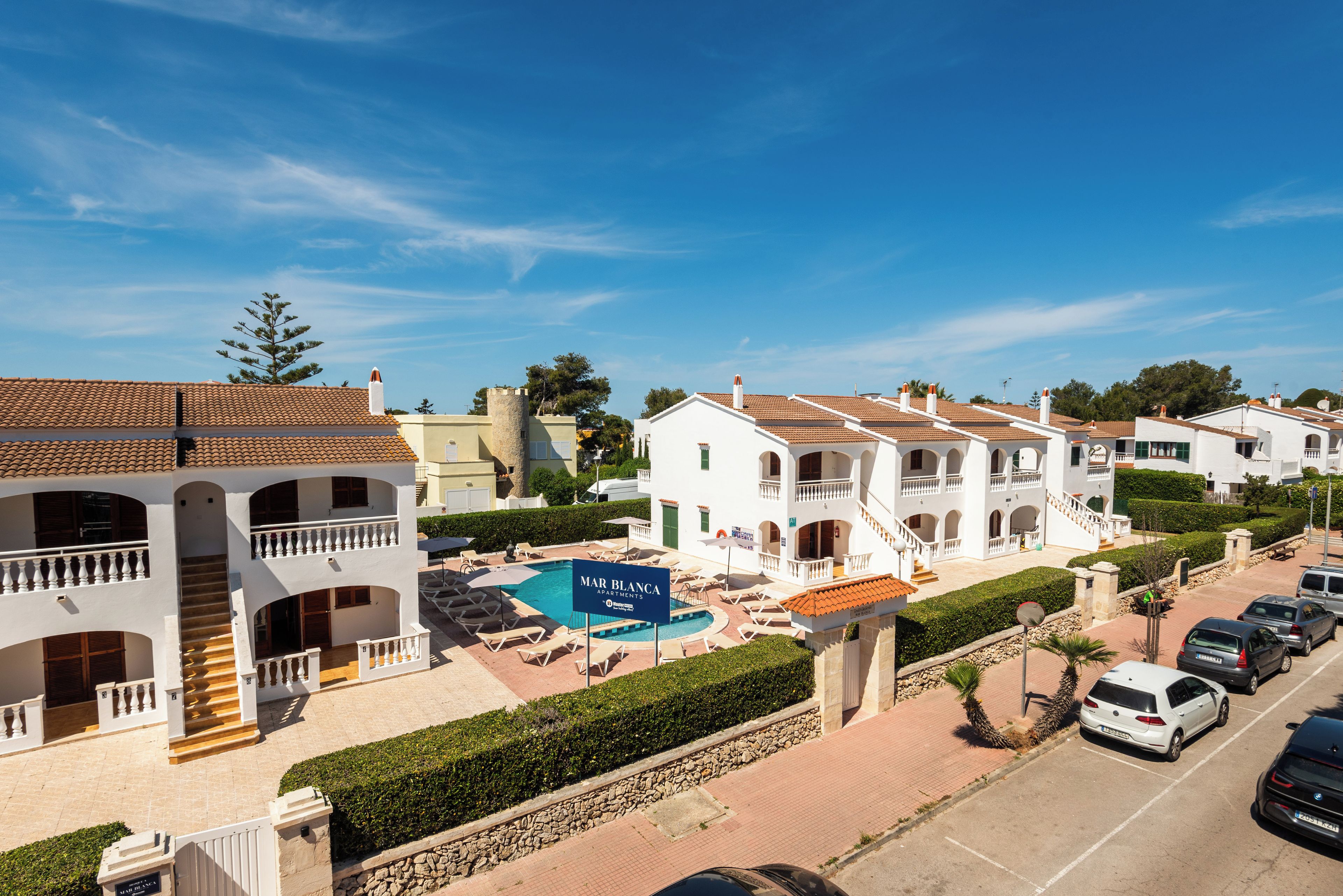 Área residencial com piscina, vários edifícios com varandas e céu limpo.