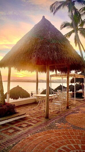 A beachside patio with a thatched umbrella, lounge chairs, and a view of the ocean. - Bungalows Princess (Bucerías)
