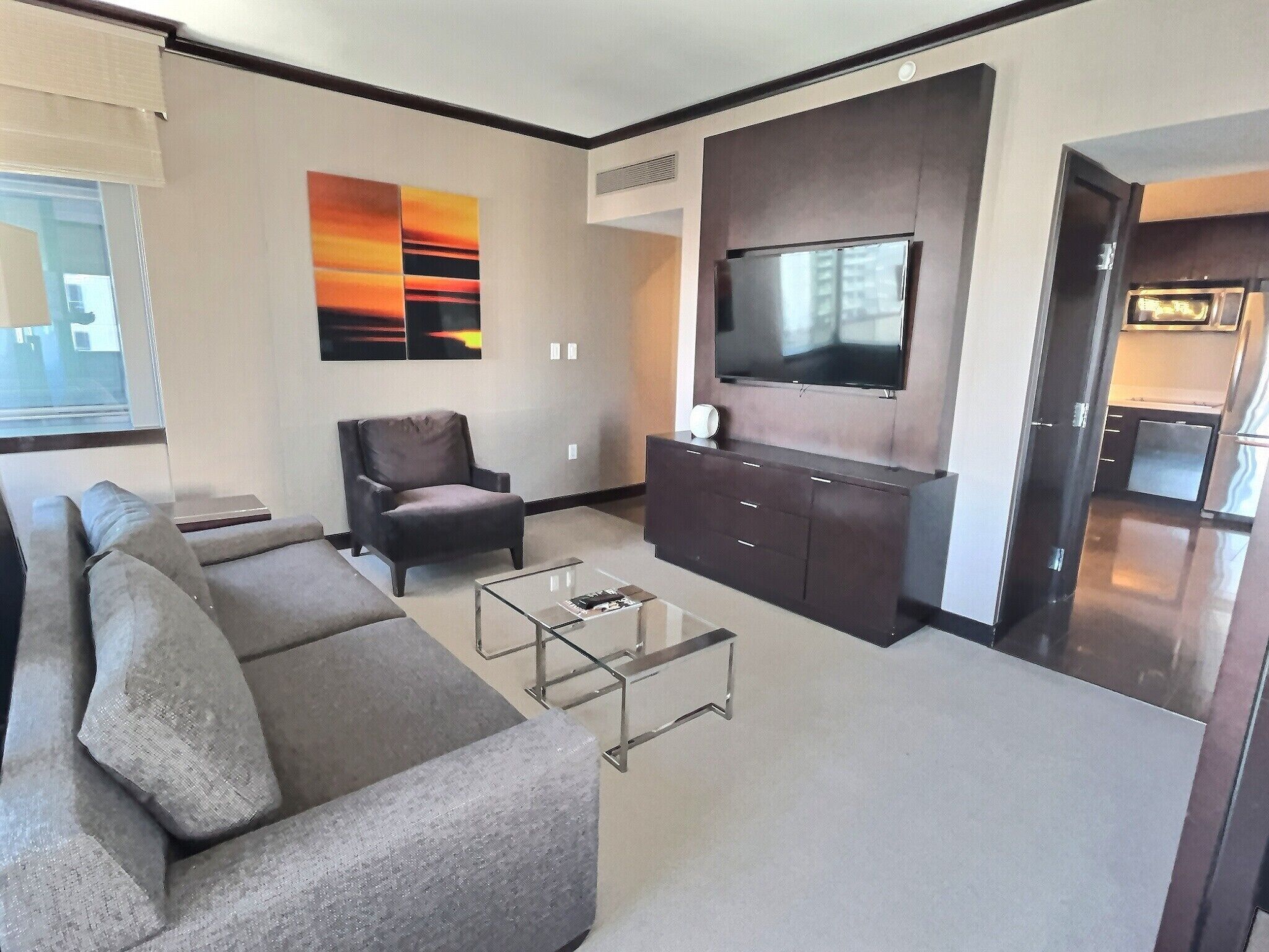 Uma sala de estar moderna com sofá, mesa de centro, televisão e obra de arte na parede.