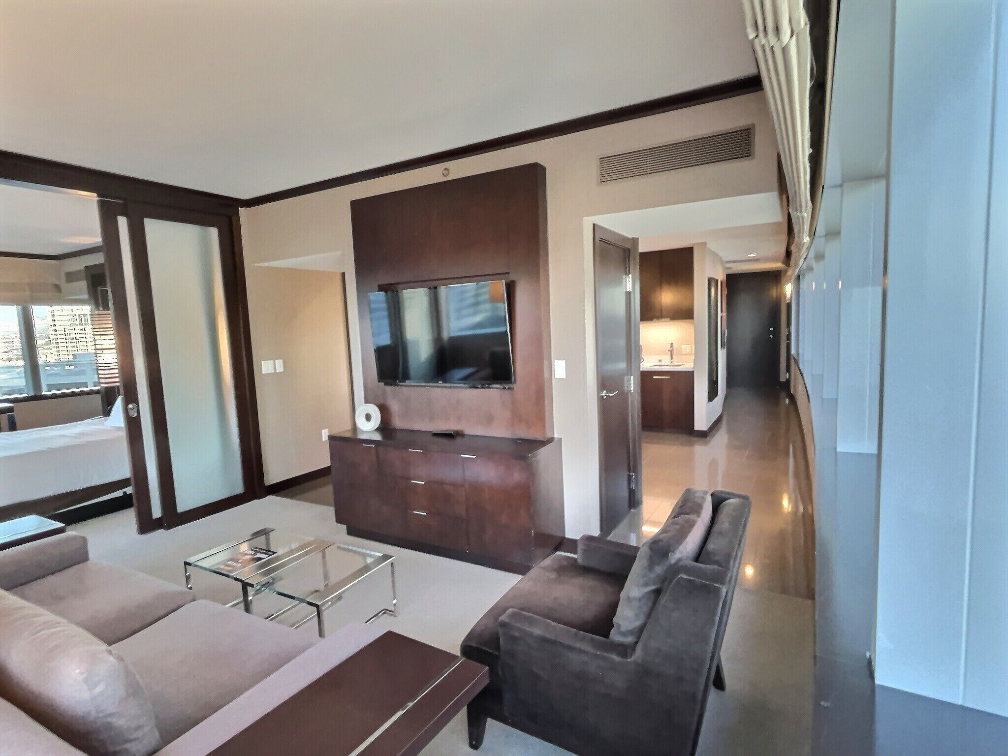 A modern living room with a flat-screen TV, a sofa, a coffee table, and a built-in entertainment unit.