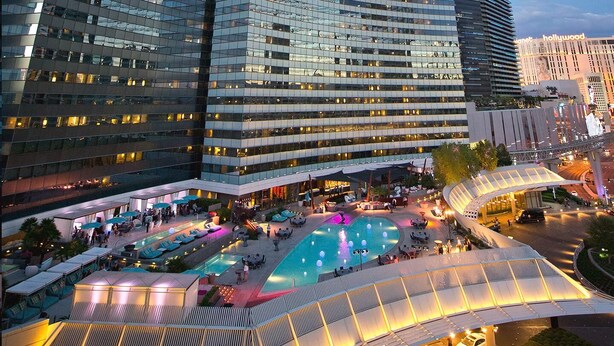 A hotel with a rooftop pool, outdoor seating, and a modern architectural design.