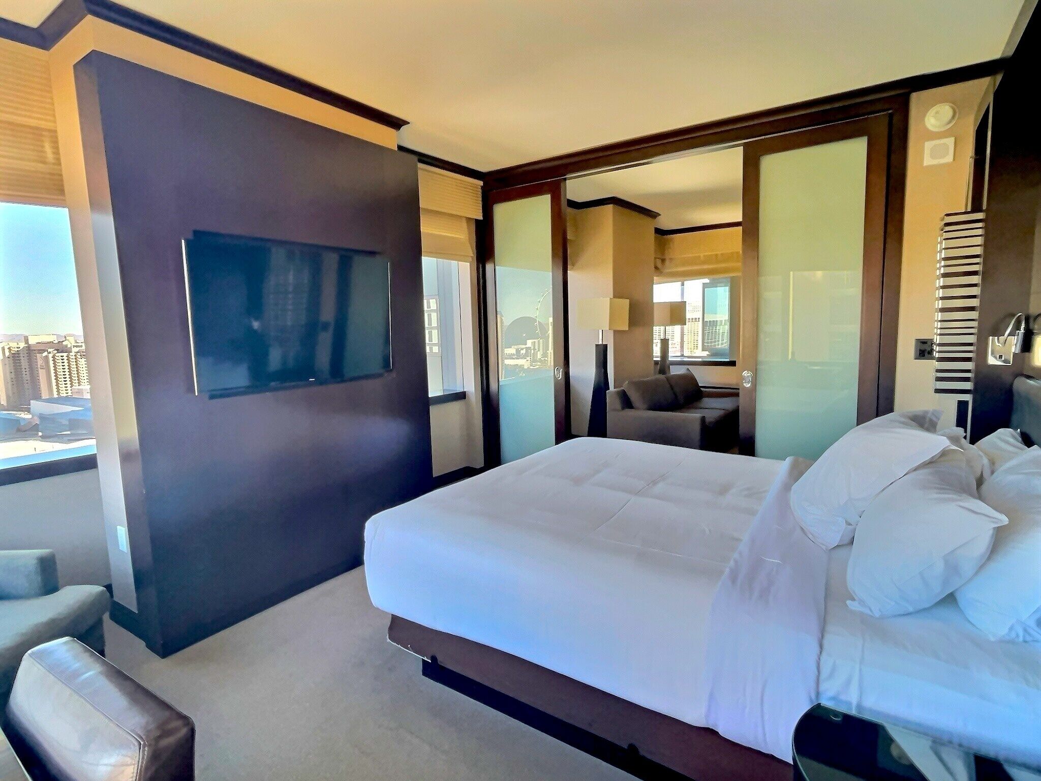 A modern hotel room with a large bed, a seating area, and a view of the city.