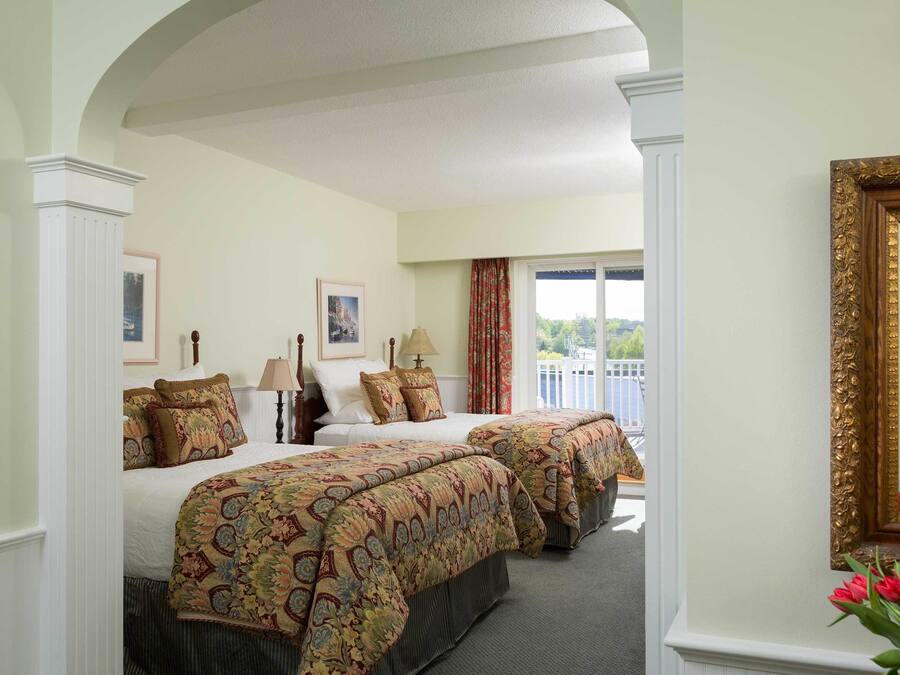 A hotel room with two beds, a large window, and a balcony.