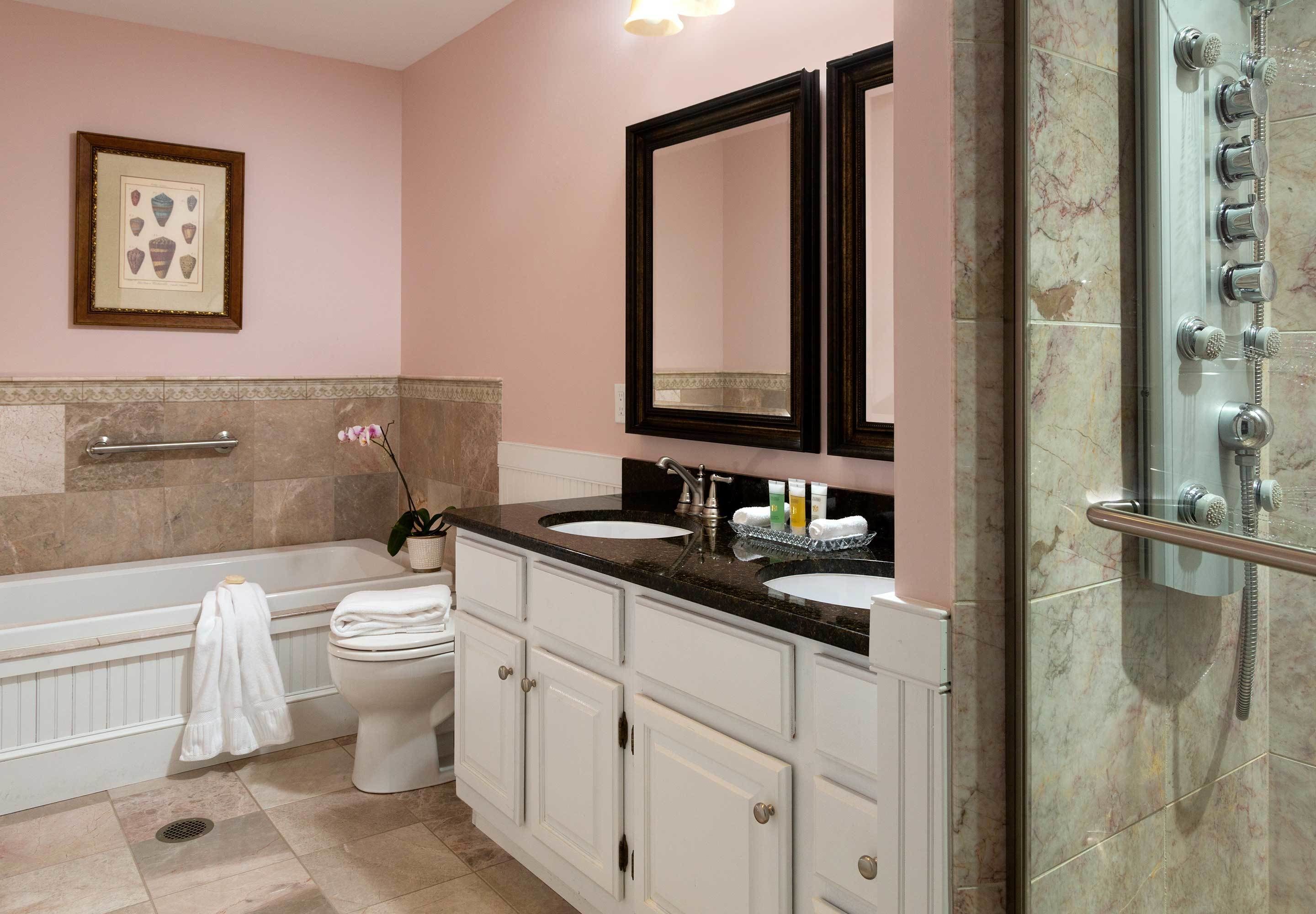 A bathroom with a bathtub, two sinks, a toilet, and a shower.