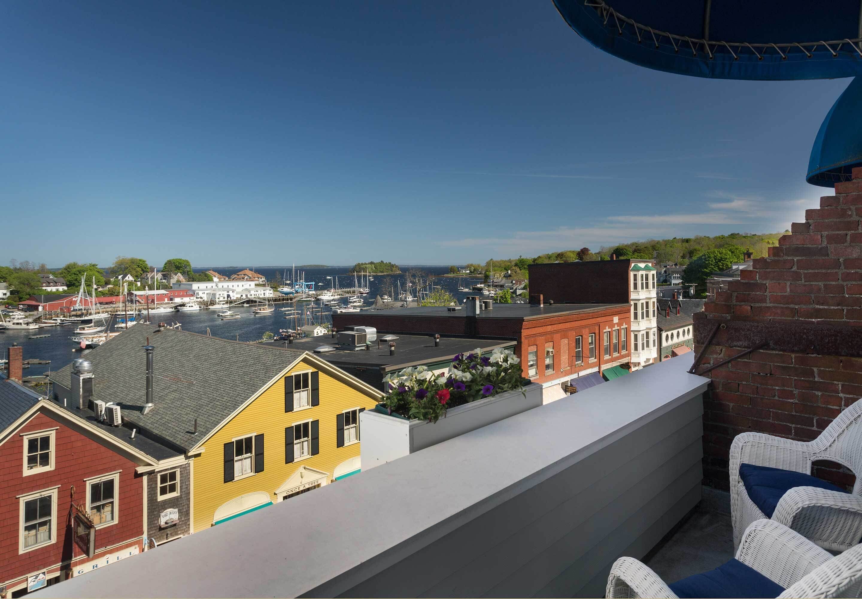 A balcony with wicker furniture overlooking a marina with boats and buildings.