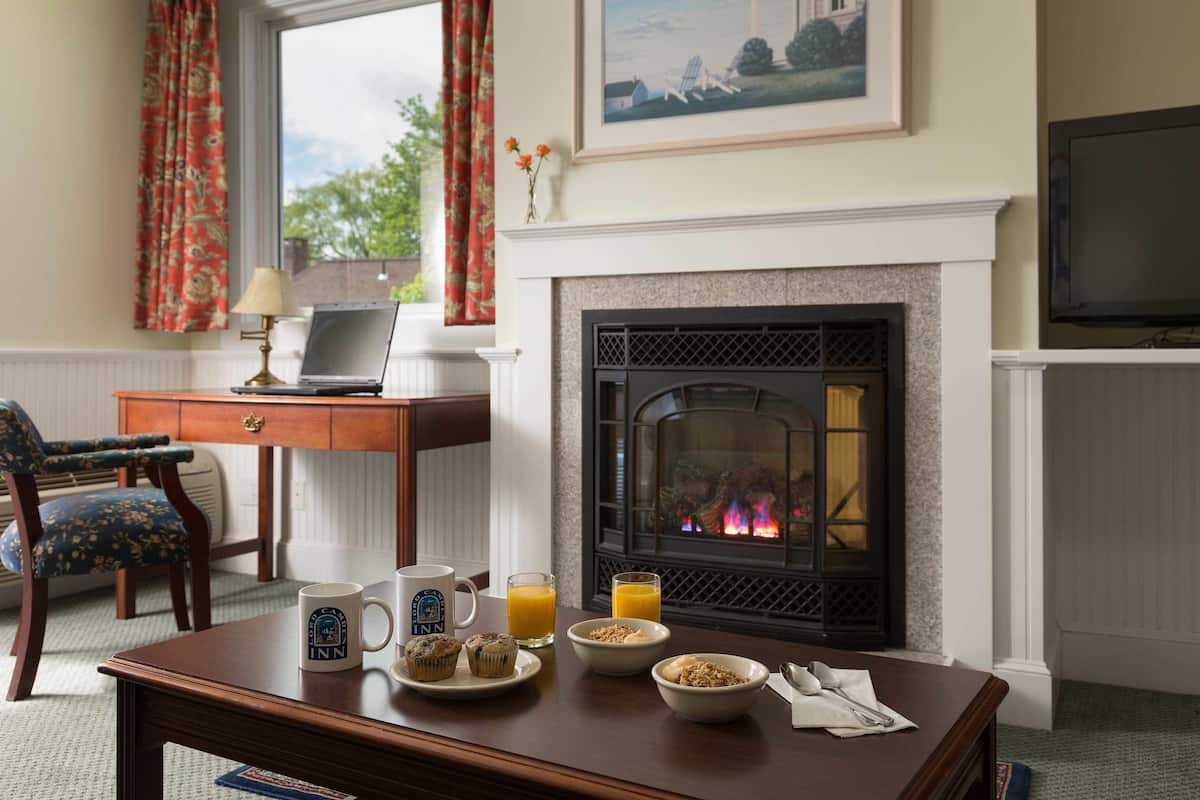 Una habitación acogedora con chimenea, una mesa de comedor con alimentos para el desayuno, una computadora portátil y un televisor.