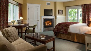 A cozy room with a fireplace, a bed, a sofa, and a desk with a laptop. - Lord Camden Inn (Camden)