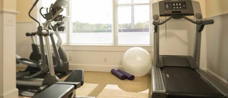 A home gym with exercise equipment including a treadmill, elliptical, and dumbbells.