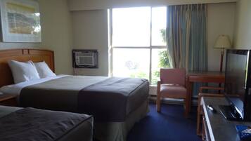 A hotel room with a large bed, a desk with a laptop, a chair, and a television.