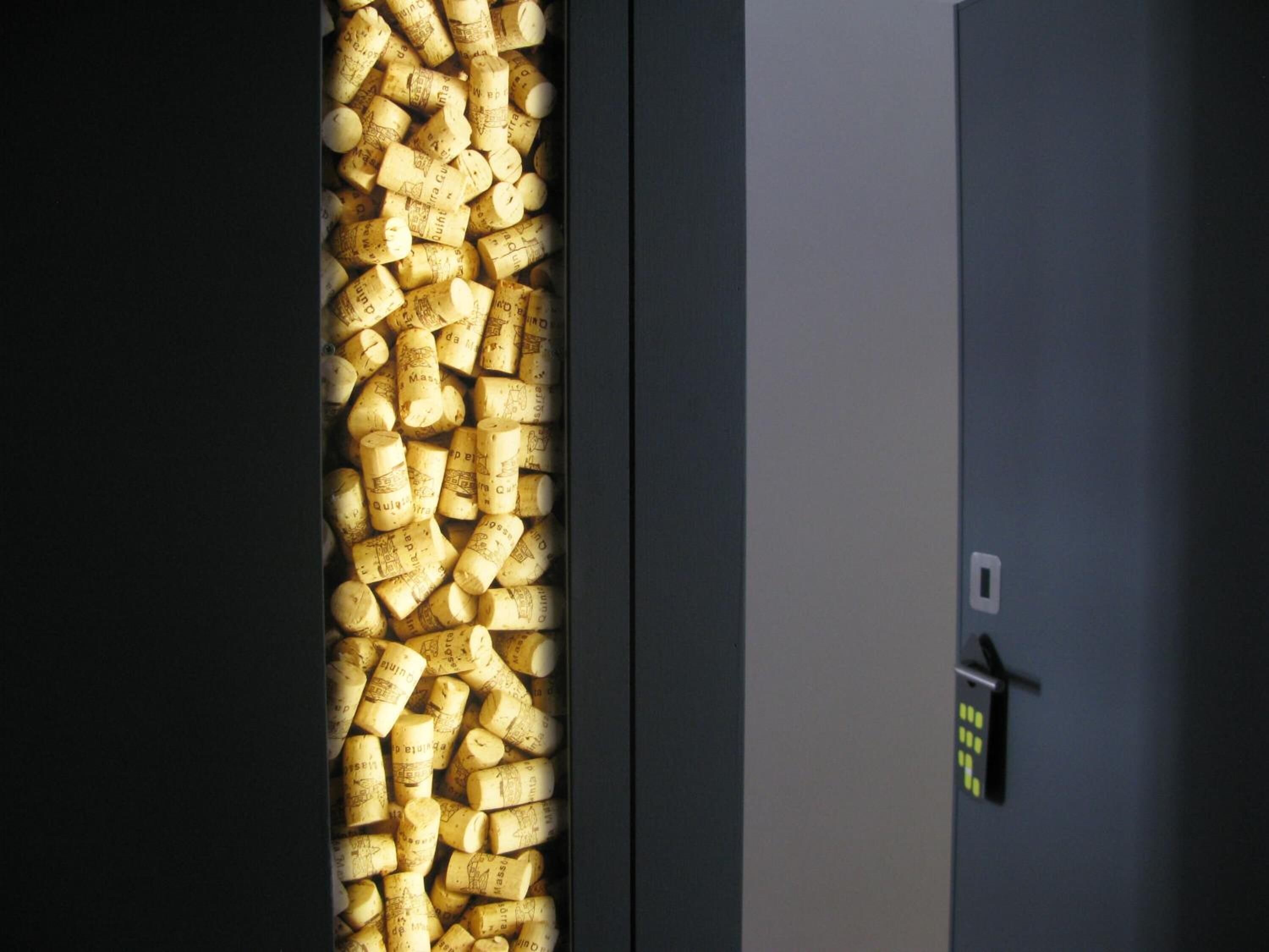 A wall with numerous wine corks arranged vertically.