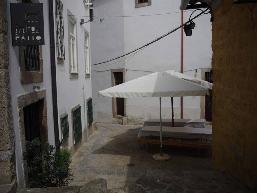 Un patio estrecho con una sombrilla blanca y una cama.