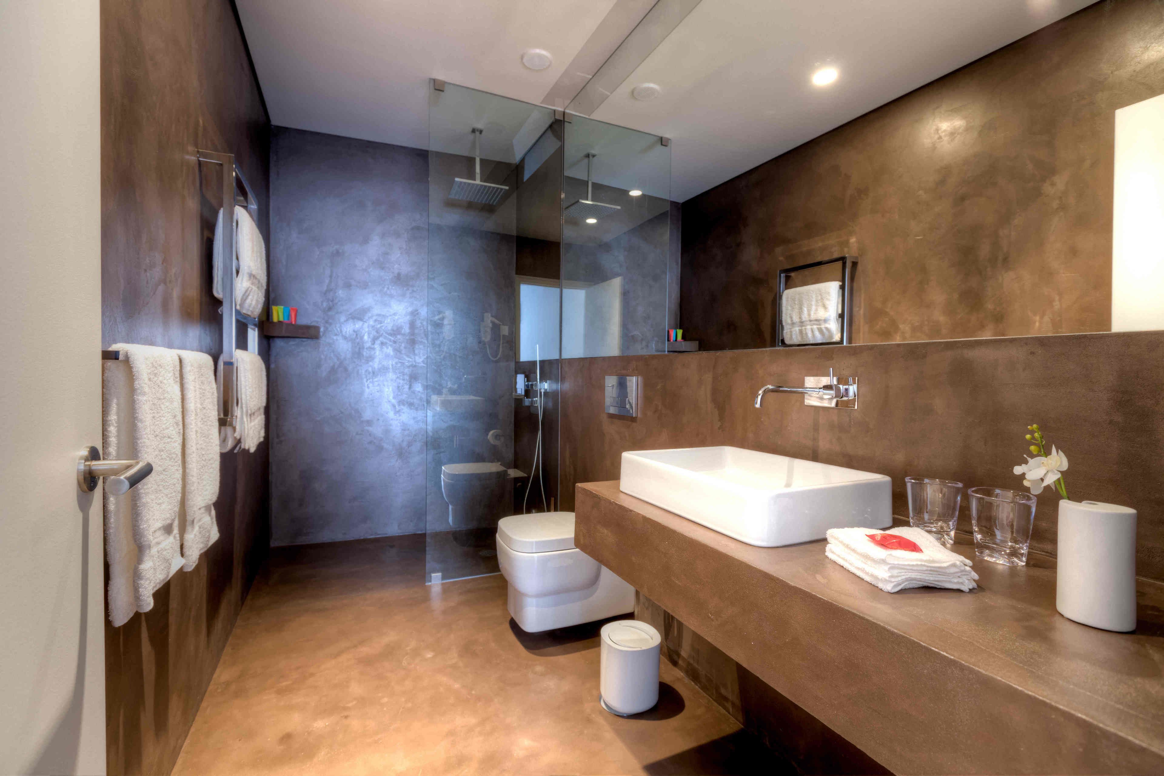 Une salle de bain moderne dotée d’un grand lavabo, d’une douche à parois de verre et de toilettes.