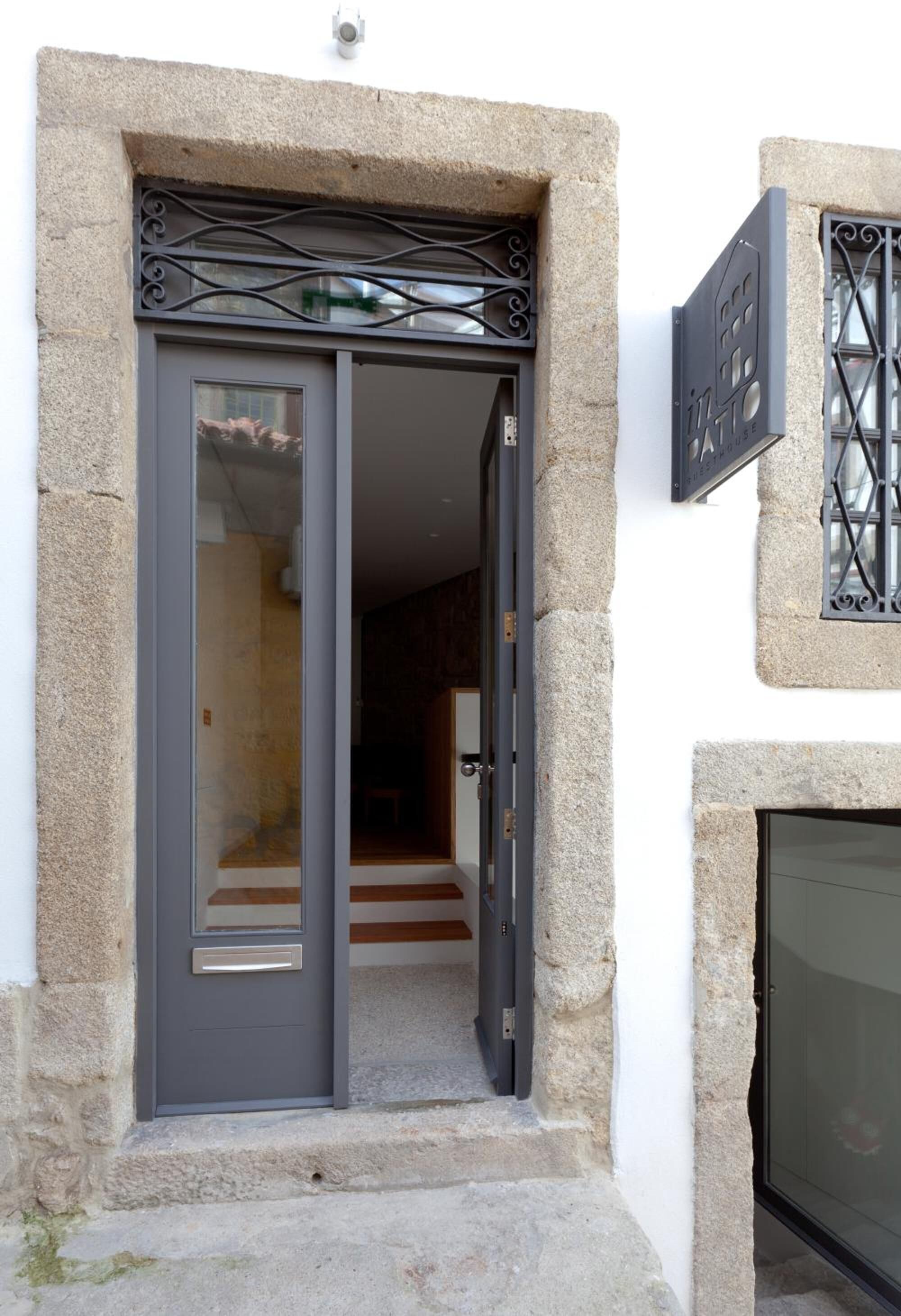 A stone-framed entrance with a sliding glass door, a small step leading up to the door, and a metal gate above the door.