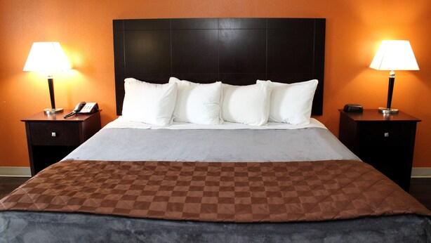 A hotel room with a large bed, two bedside tables, and two lamps. - Scottish Inns Killeen near Fort Cavazos (Killeen)