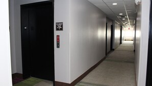 A hotel hallway with a black elevator door, a fire emergency sign, and a red emergency button. - Scottish Inns Killeen near Fort Cavazos (Killeen)