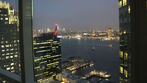 A nighttime cityscape with high-rise buildings and a river. - Green Suites (Jersey City)