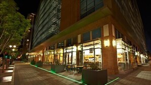 A modern hotel with outdoor seating and illuminated windows at night. - Green Suites (Jersey City)