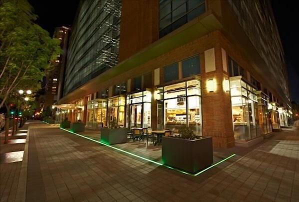 A modern hotel with outdoor seating and illuminated windows at night.