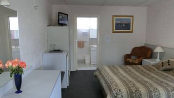 Ein Hotelzimmer mit Bett, Schreibtisch, Stuhl, Fernseher und einem durchgegangenen Tür sichtbaren Badezimmer.