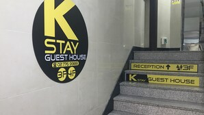 A hotel sign with a black and yellow logo, a reception sign, and a guest house sign on a staircase.