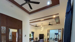 A spacious living area with a dining table, chairs, ceiling fans, and a TV. - Padimas Villa @Datai Valley (Langkawi)