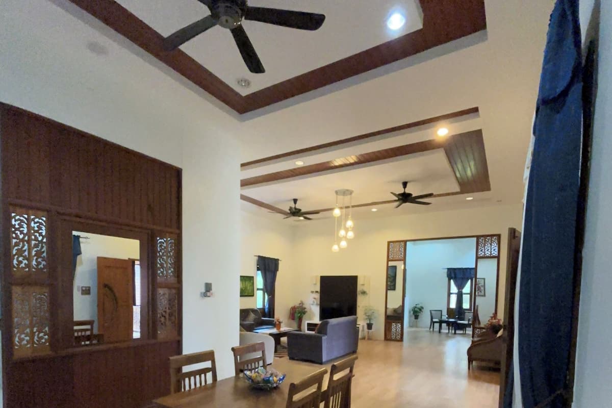 A spacious living area with a dining table, chairs, ceiling fans, and a TV.