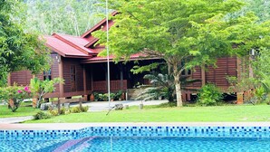 A wooden house with a red roof, surrounded by lush greenery and a swimming pool. - Padimas Villa @Datai Valley (Langkawi)