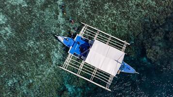 Vista aérea de una estructura flotante con un espacio central abierto, rodeada de aguas claras y un lecho rocoso.
