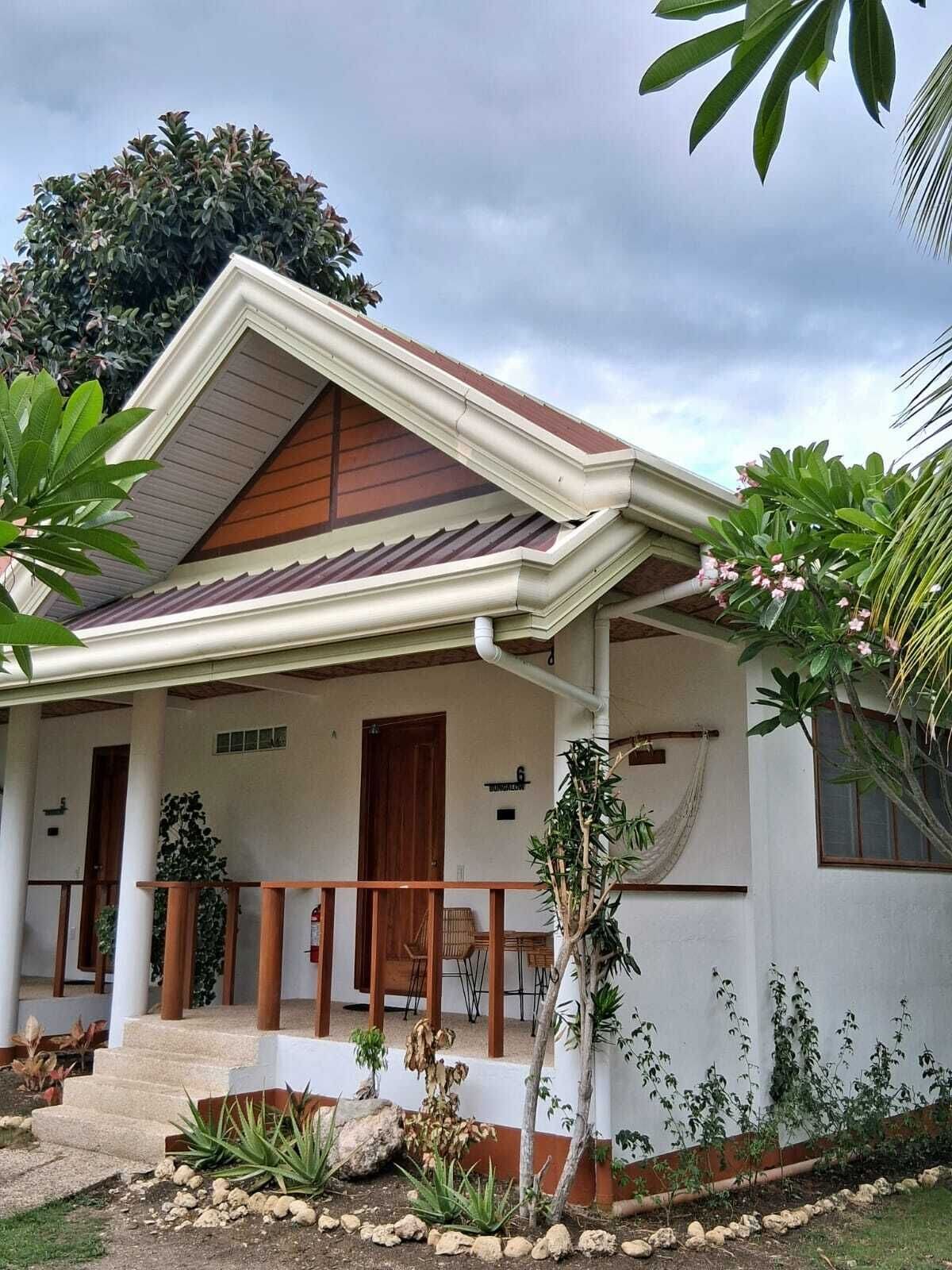 A house with a porch, a wooden door, and a number sign.