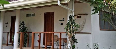 A house with a porch, a wooden door, and a number sign.