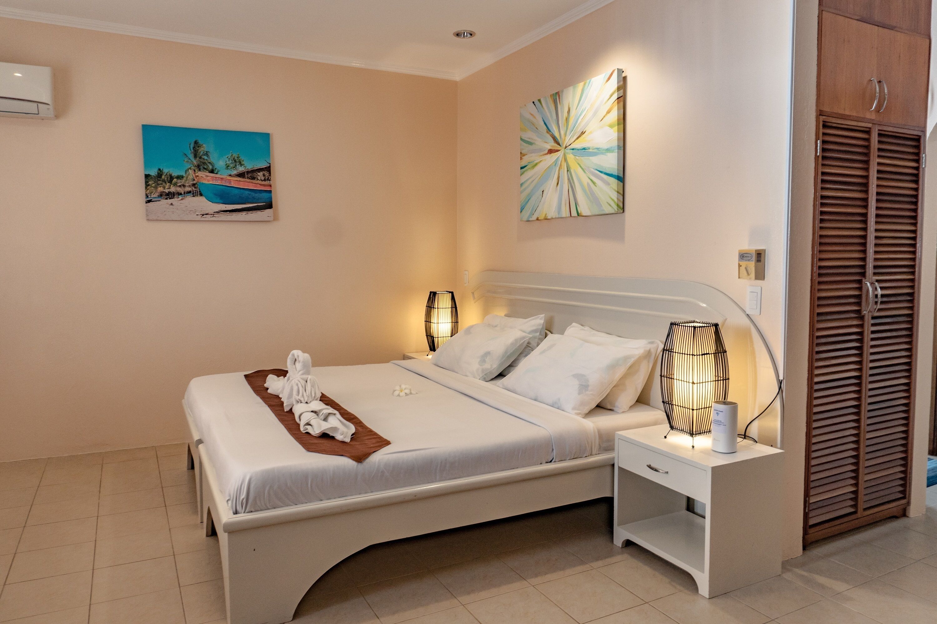 A neatly arranged bedroom with a bed, bedside lamps, a nightstand, and a wardrobe.