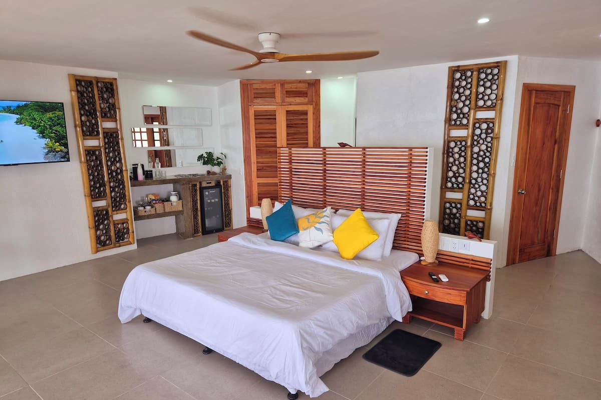 Een ruime slaapkamer met een groot bed, een houten hoofdbord en een plafondventilator.