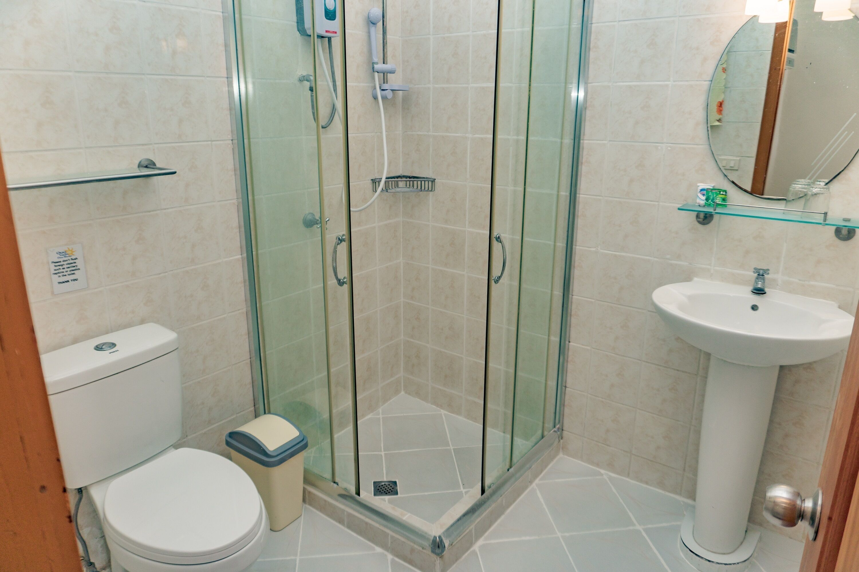 A bathroom with a glass-enclosed shower, a white sink, and a toilet.