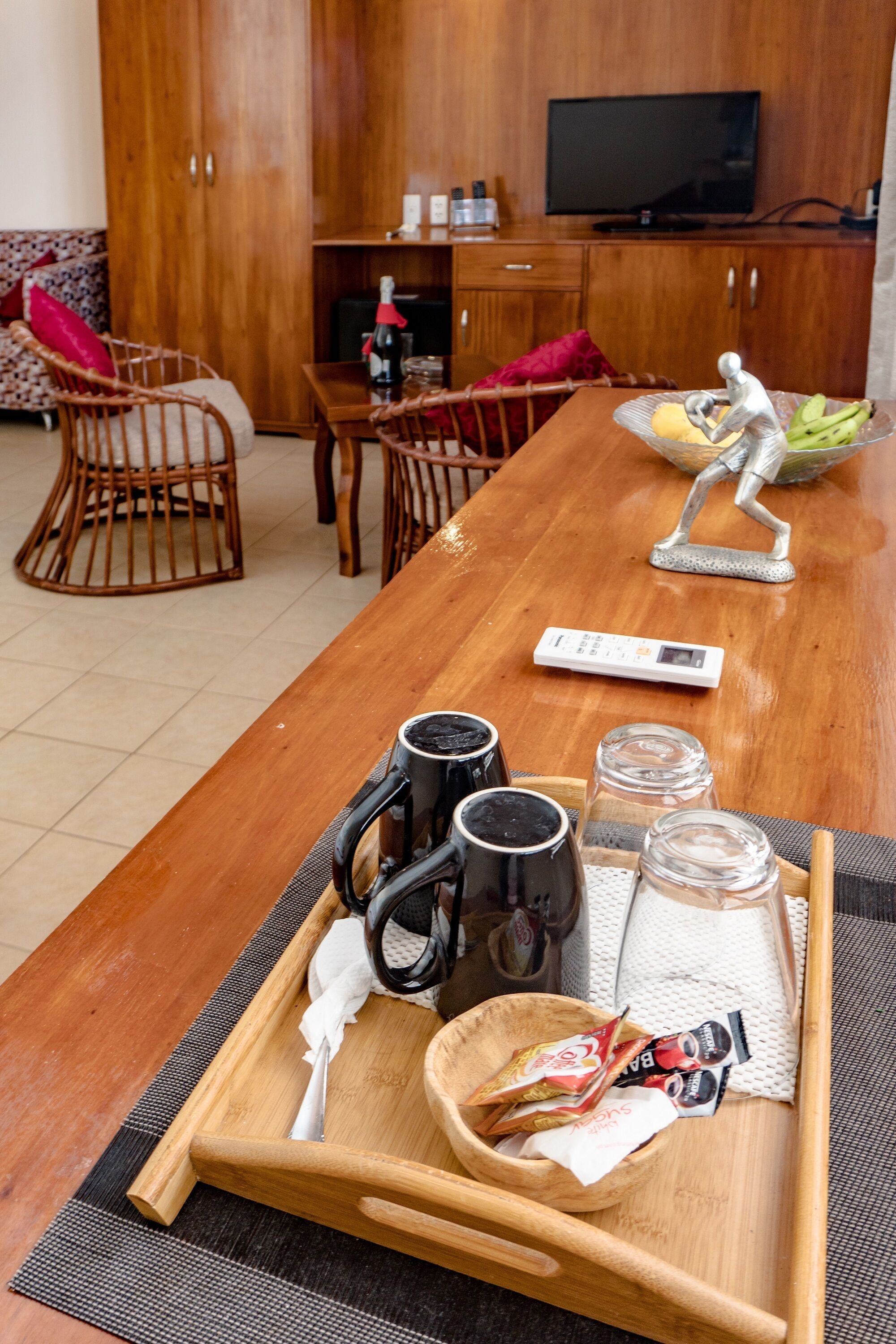 A wooden dining table with a tray containing mugs, glasses, and snacks.