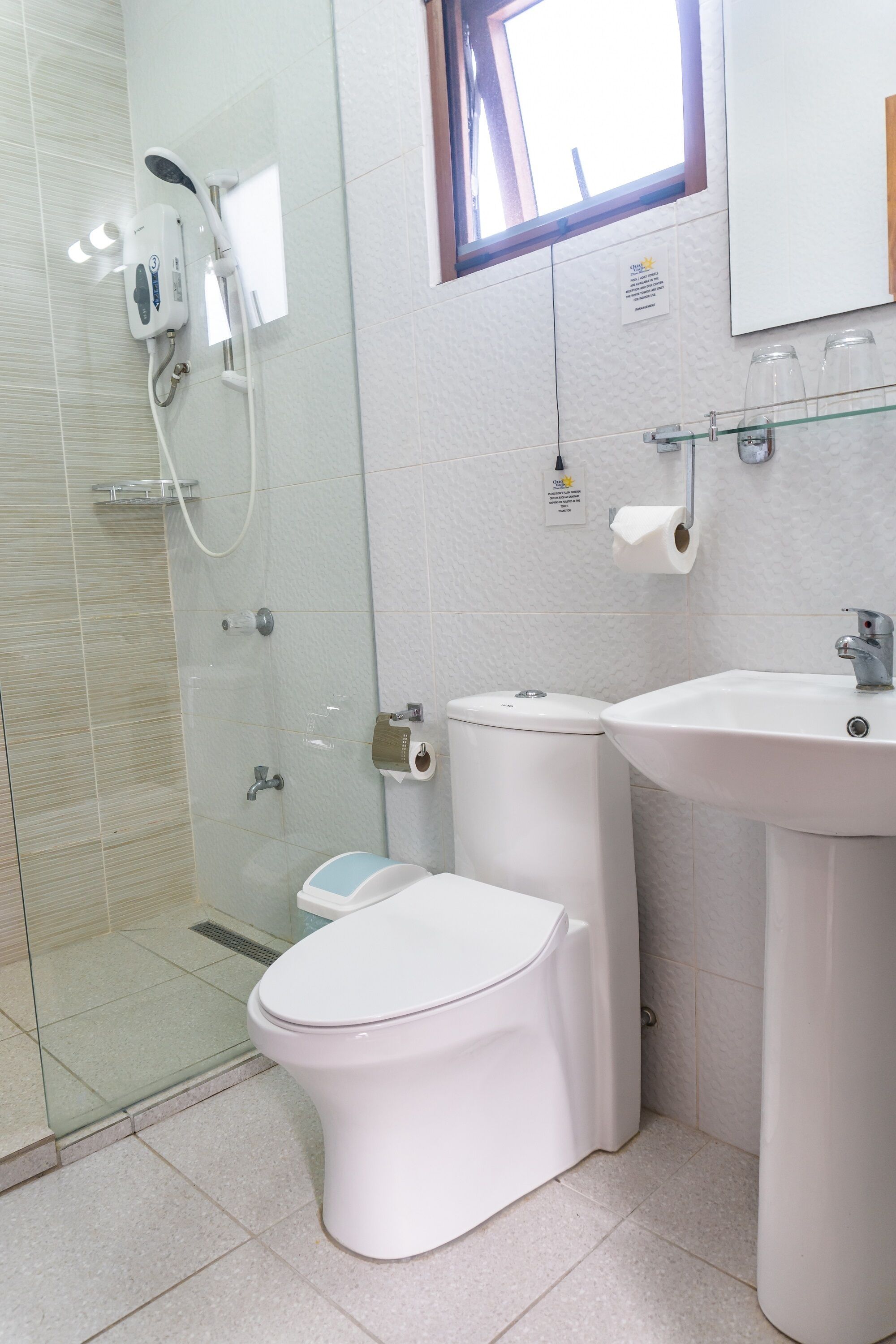 Un baño moderno con ducha envuelta en vidrio, inodoro blanco y lavamanos con espejo.
