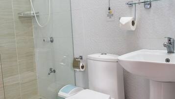 A modern bathroom with a glass-enclosed shower, a white toilet, and a sink with a mirror above it.