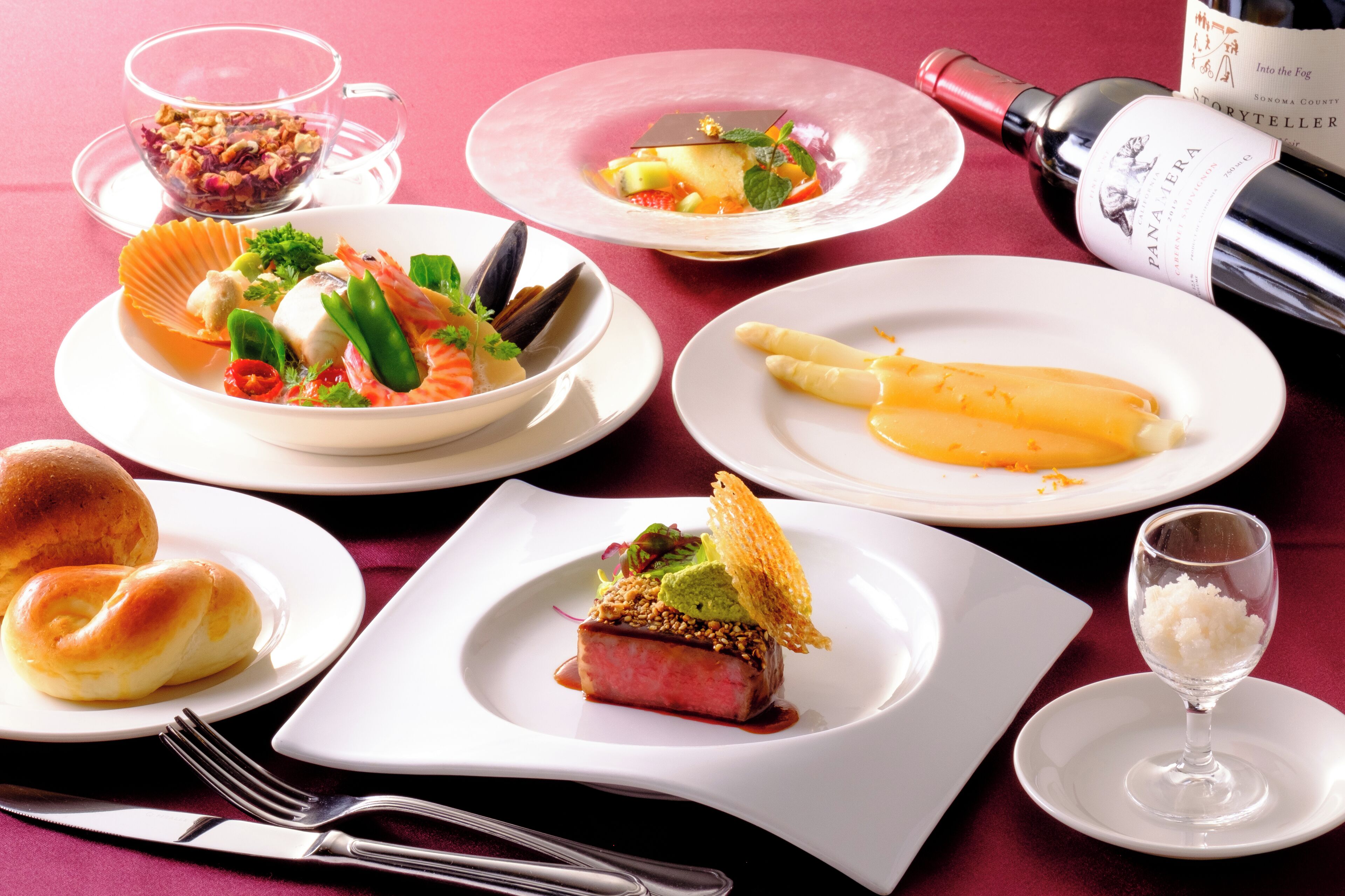 A table set with various dishes, including seafood, vegetables, and a bottle of wine.