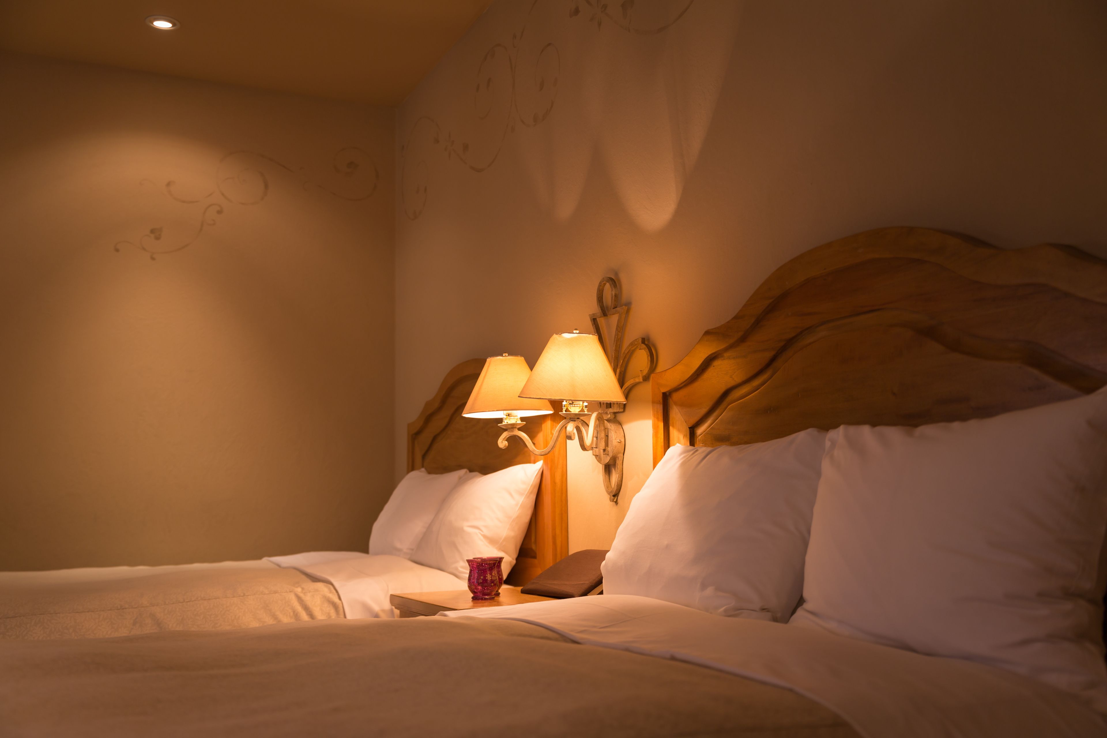 A hotel room with a bed, two bedside lamps, and a decorative wall.