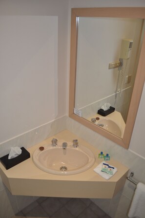 Un baño con lavamanos, espejo y perchero para toallas.