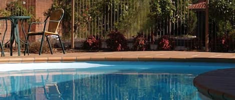 Una piscina al aire libre de temporada, sillones reclinables de piscina