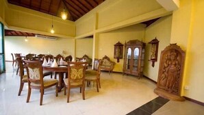 Un comedor espacioso con mesas y sillas de madera, techo alto con vigas a la vista y lámparas de pared de estilo tradicional.