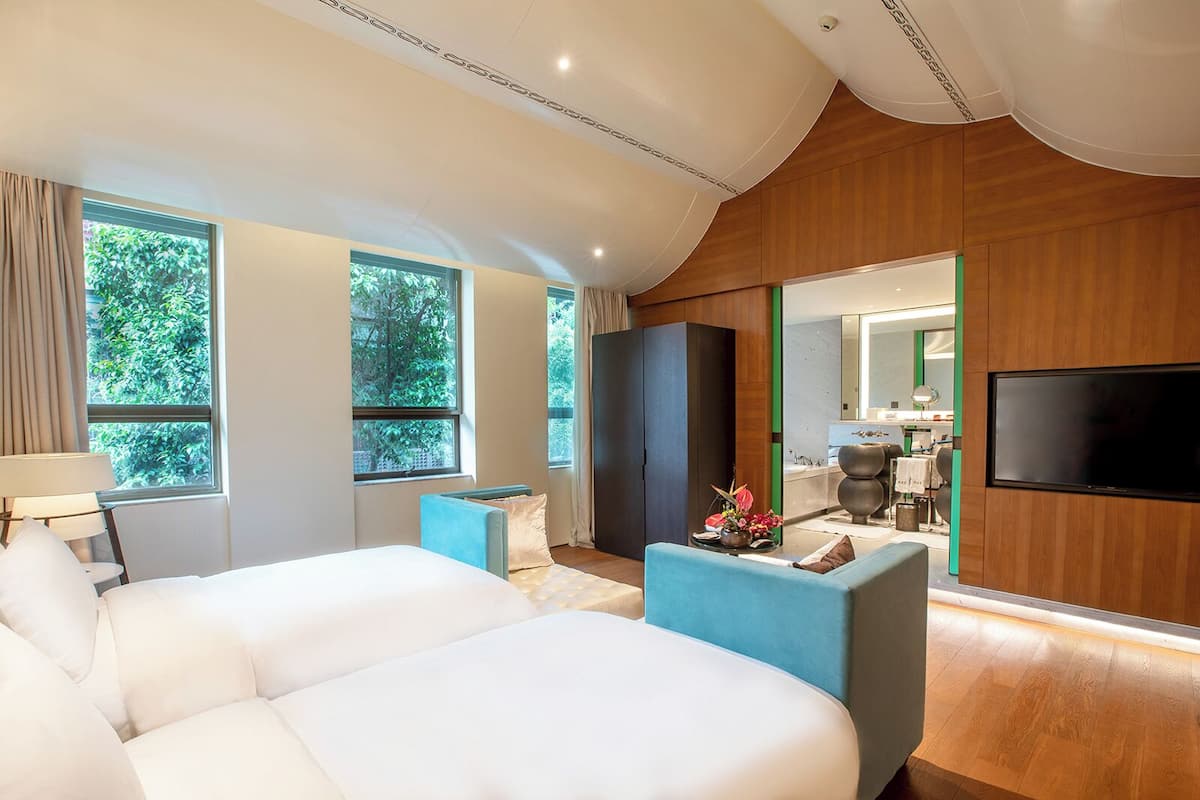Une chambre d’hôtel moderne dotée d’un grand lit, d’un coin salon, d’une télévision et offrant une vue sur l’extérieur.
