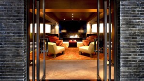Un intérieur moderne avec une cheminée, des canapés en cuir et une arche en briques.