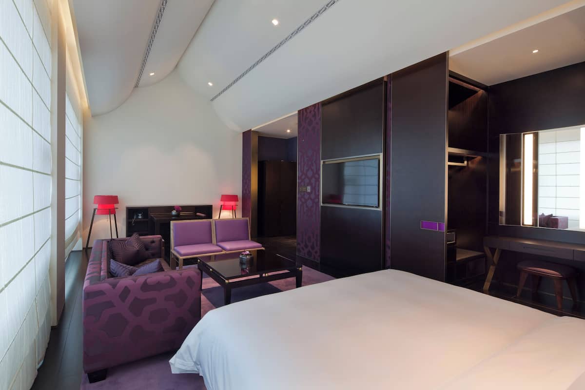 Une chambre d’hôtel moderne, dotée d’un grand lit, d’un canapé, d’un bureau et d’une télévision.