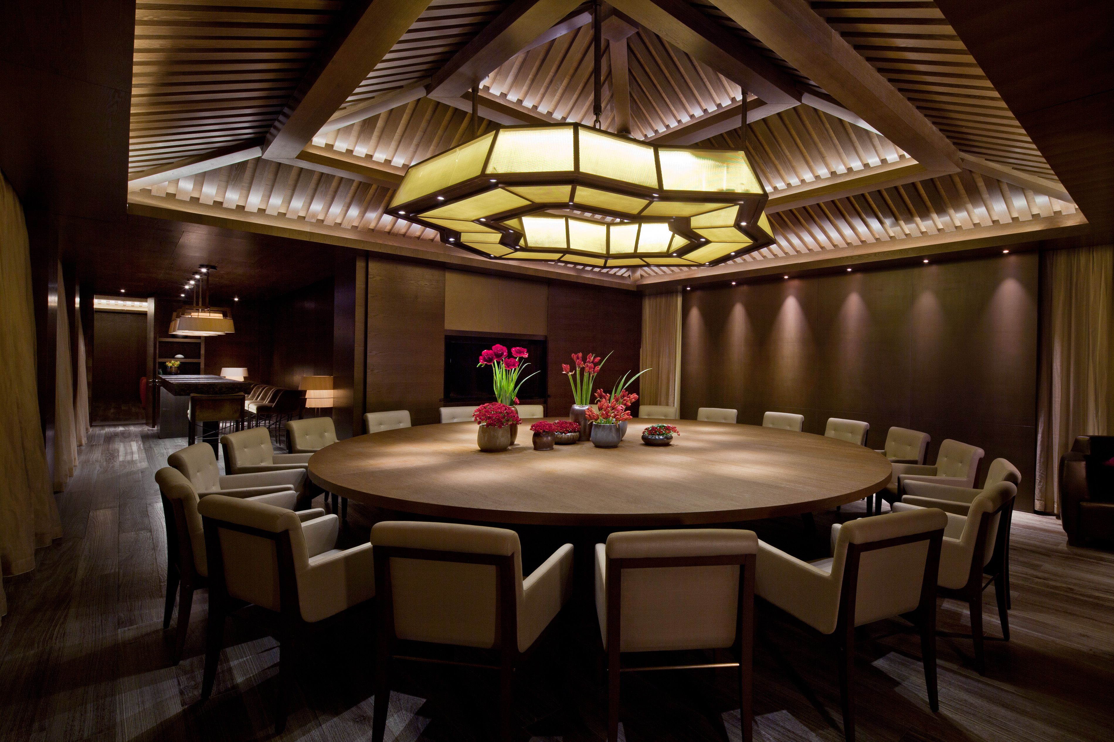 A conference room with a round table, chairs, and a modern chandelier.
