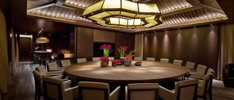 A conference room with a round table, chairs, and a modern chandelier.