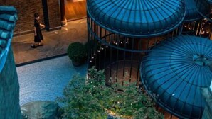 Un bâtiment traditionnel doté de plusieurs structures circulaires, qui pourraient former une cour ou un jardin, et une personne marchant au premier plan.