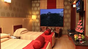 A hotel room with two beds, a TV, a desk with a computer, and a flower vase. - Hotel Basant Residency (Bengaluru)