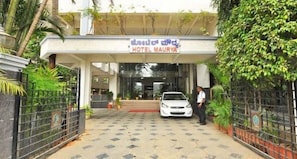 The entrance to Hotel Maurya with a car parked in front and a person standing near the entrance.