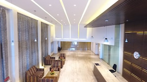 A spacious lobby with a reception desk, seating area, and a large window providing a view of the interior.